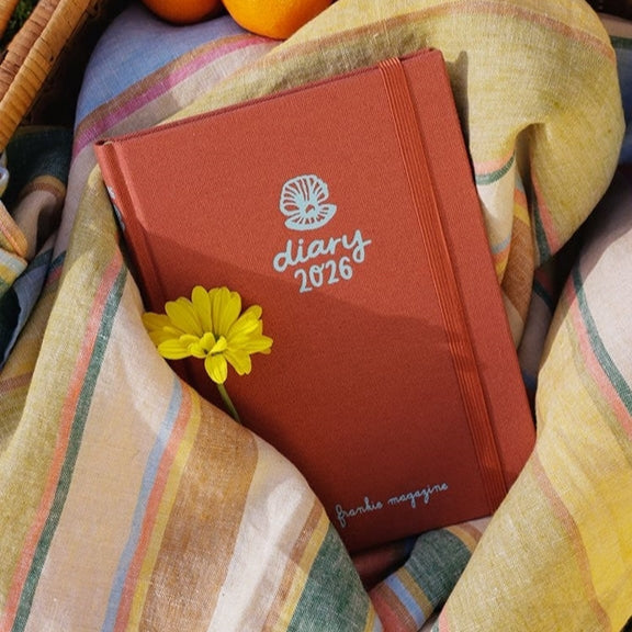 Frankie Diary 2026 nestled in striped linen fabric with a yellow flower.