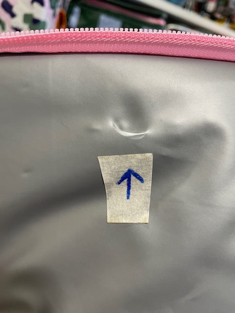 Close up of Lid lining of the Imperfect Mini tote with an arrow sticker pointing to crescent moon shaped fold approx 10mm wide.