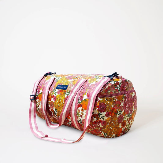 side view of Floral patterned duffel bag with pink straps on a white background