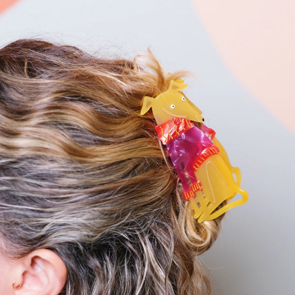 A hair claw shaped like a Greyhound wearing a knitted jumper in light wavy hair.