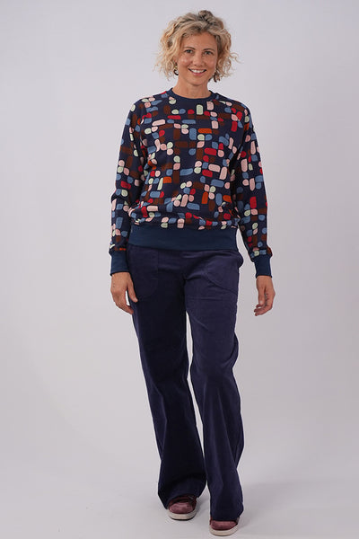 Full length image of model wearing Essaye Abstract Sweater in Blue, and dark blue pants