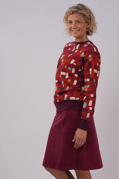 Side view of model wearing Essaye Abstract Sweater in Red