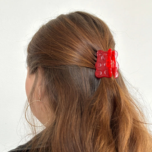 Red gummy bear hair clip on a person's hair against a white background