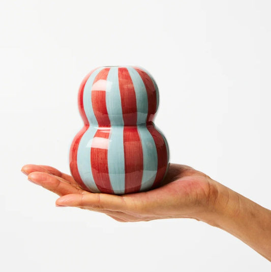 Red and white striped ceramic object held in a hand against a white background