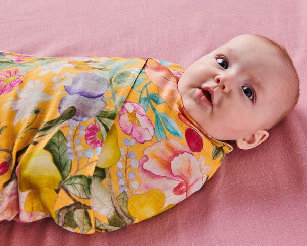 Close up of Kip & Co Abundance Marigold Bamboo Baby Swaddle modelled by baby.