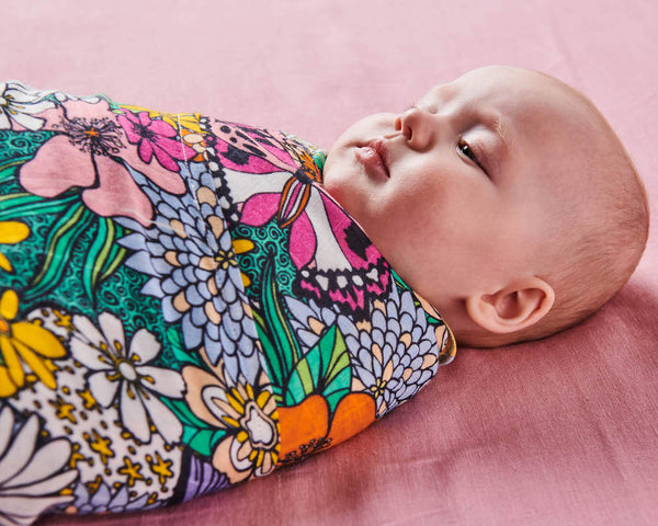 Close up of Kip & Co Bliss Floral Bamboo Baby Swaddle modelled by baby