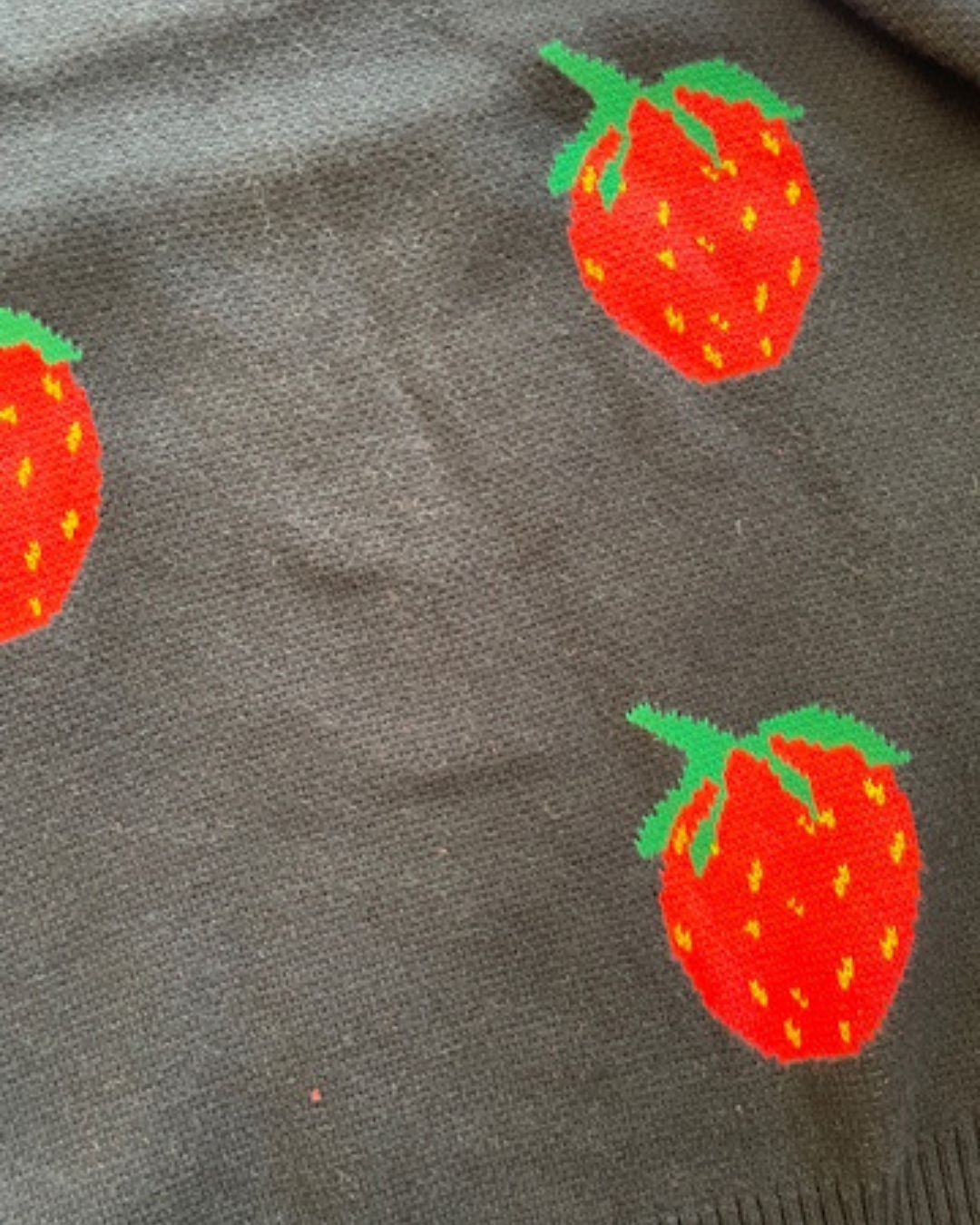 Close up of Black knit jumper with red strawberry patterns