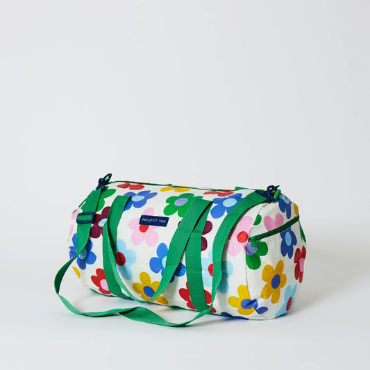 Colorful floral-patterned duffel bag with green straps on a white background