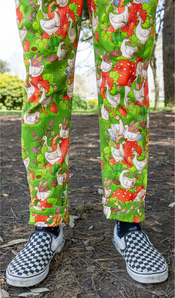 Close up of the pant legs of Run and Fly x The Mushroom Babes In The Geese Garden Stretch Twill Dungarees worn by a model. They are wearing black and white checkered sneakers on their feet.