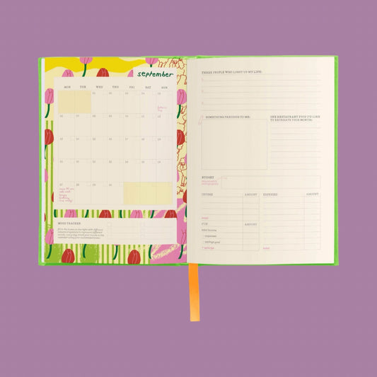 An open planner or journal spread on a solid lavender background. The left page shows a September calendar with colorful tulip illustrations and notes sections.