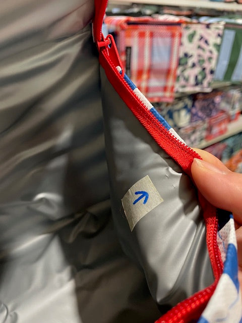 Tote lining of the Imperfect Mini tote with an arrow sticker pointing to the small cut near the zipper on the right side.