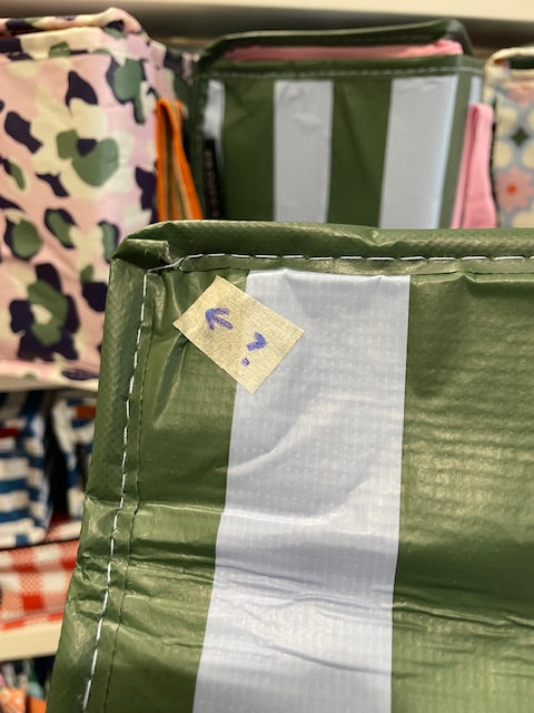 Close up of the left corner of the Base of the tote with arrow sticker pointing to the corner where the trimming has not been sewn well. 