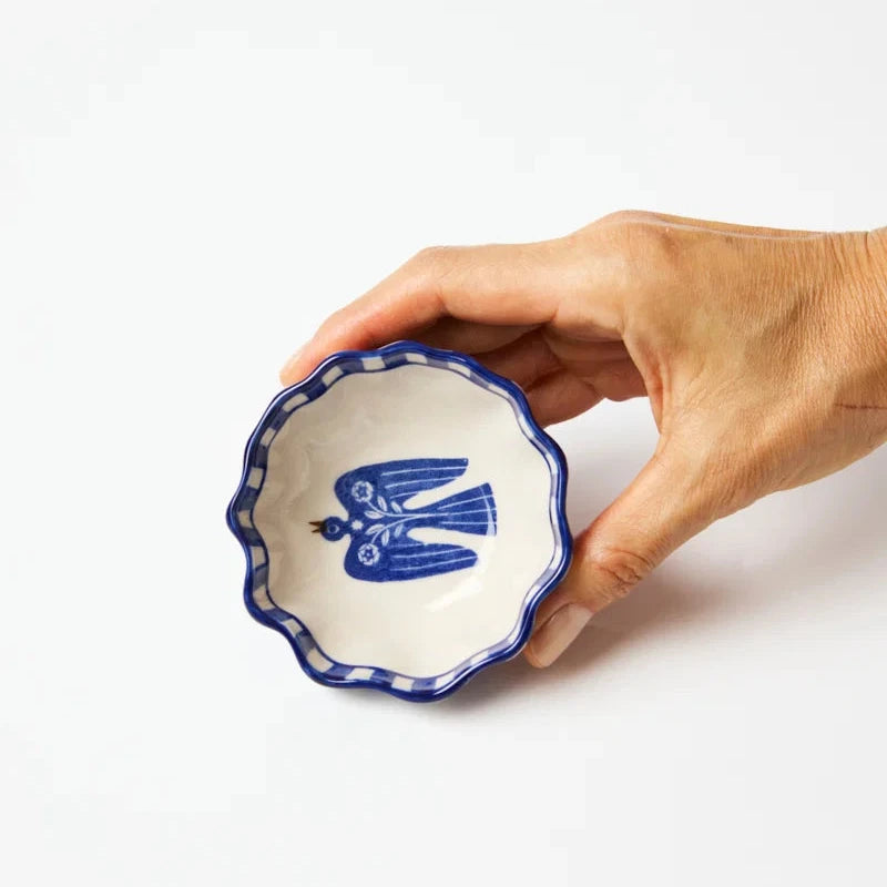 Hand holding a small ceramic bowl with blue decorative design on a white background