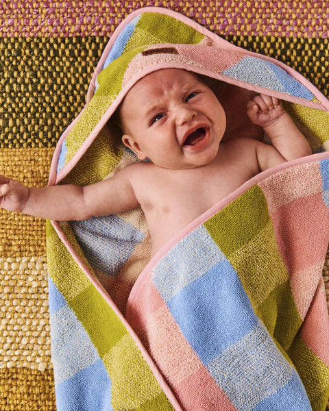 Close up of Kip & Co Corfu Tartan Terry Baby Towel wrapped around a small baby that looks like they are about to cry