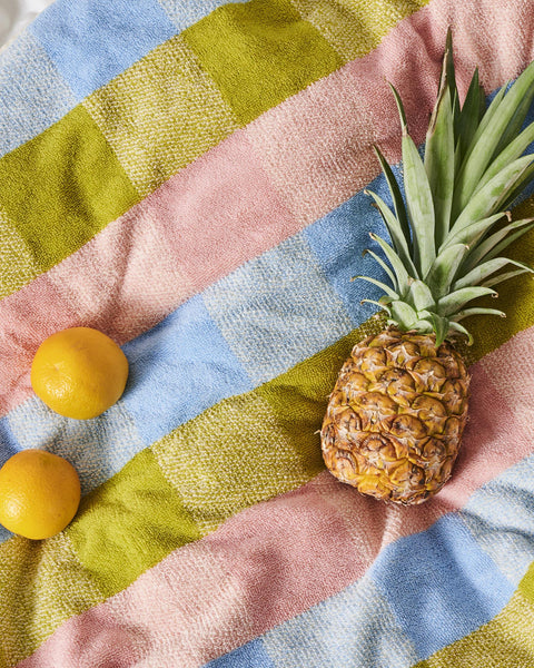 Kip & Co Corfu Tartan Terry Baby Towel styled with a pineapple and two  lemons on the towel