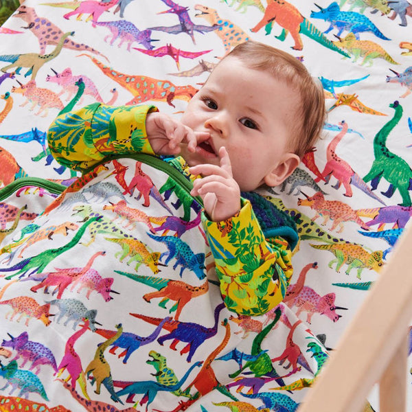 Kip & Co Dino Max Organic Cotton Snuggle Blanket covering a baby's torso.