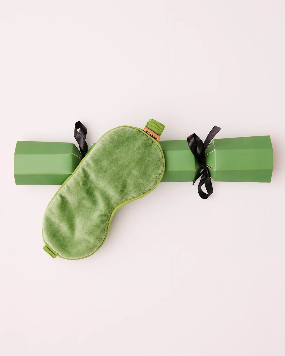 A Kip&Co Pesto Velvet Eye Mask across its matching Christmas bon-bon-shaped gift box.