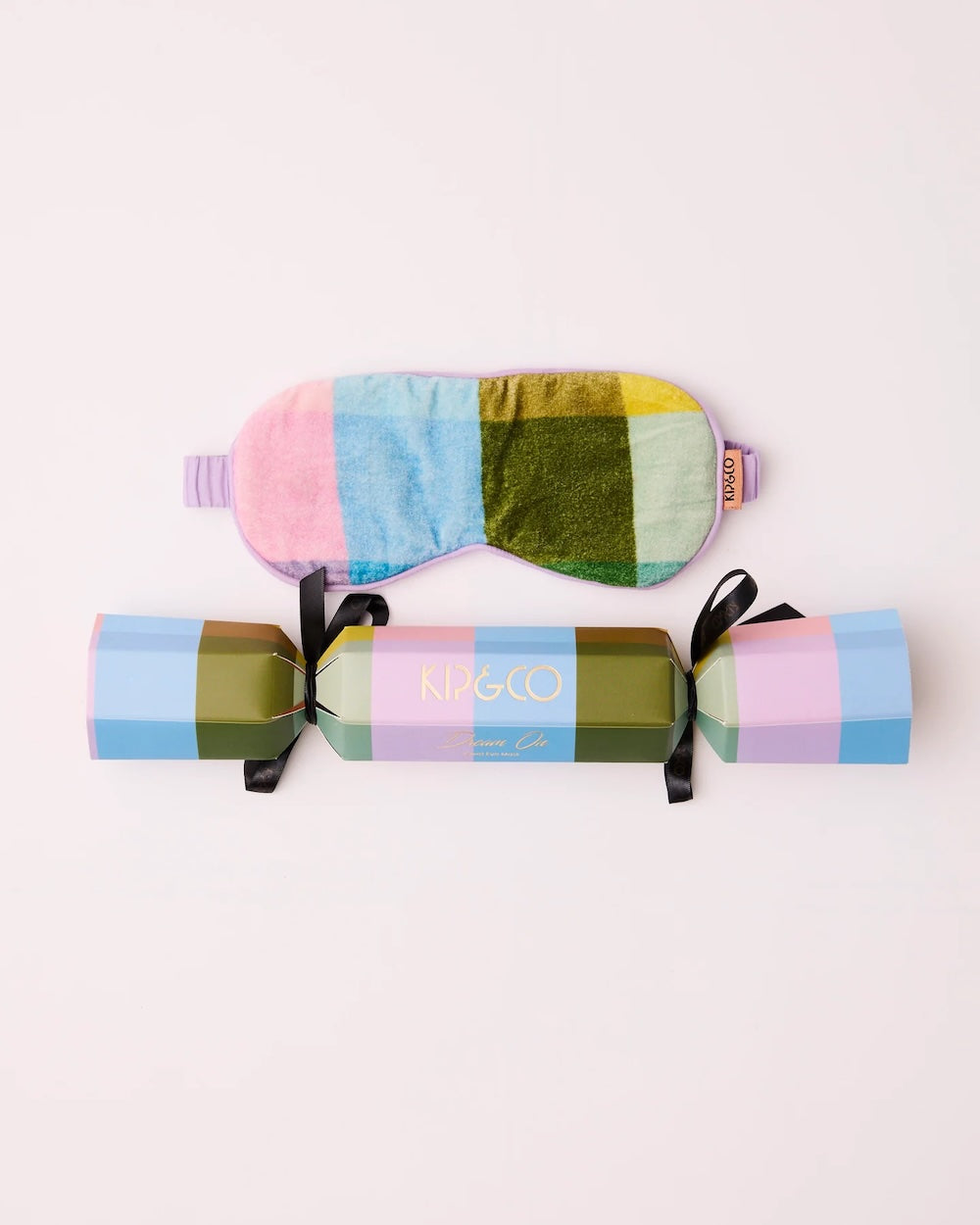 A pastel tartan velvet sleep mask and matching gift box with black ribbons, displayed on a clean off-white background. The box features the brand name 'KIP&GO' in gold foil.