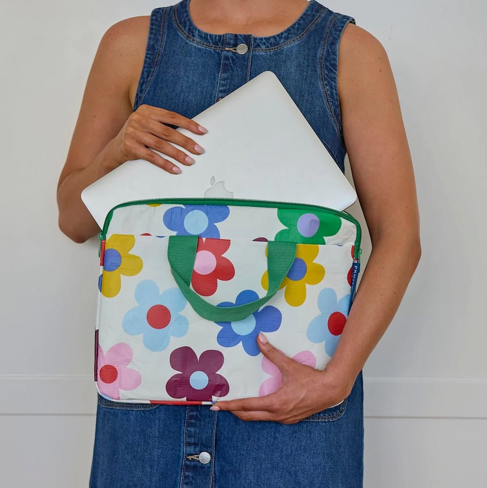 Person holding a colorful floral-patterned bag with a plain background