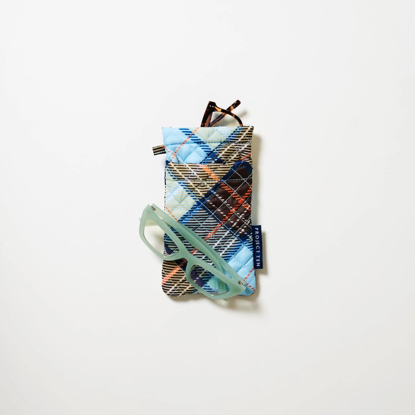 Styled image of Plaid patterned phone case with a pair of mint green glasses on the case and a pair of reading glasses peeking out from the top of the case on a white background