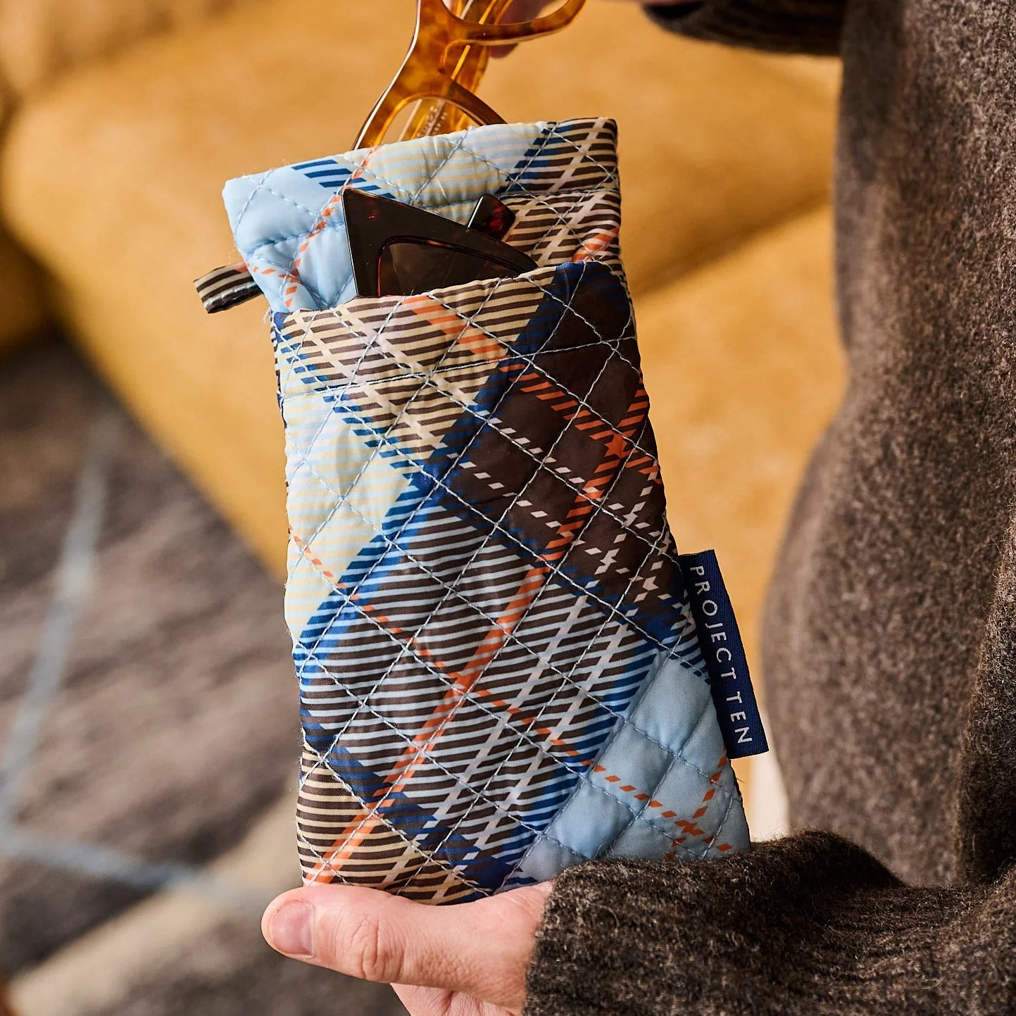 Quilted phone case with plaid pattern held by a person, brand 'Project Ten' visible