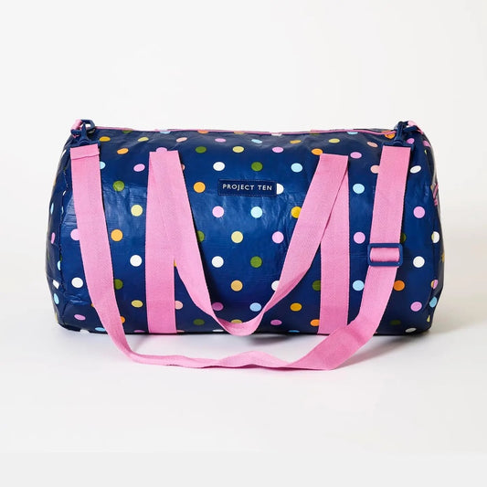 Navy duffel bag with colorful polka dots and pink straps on a white background