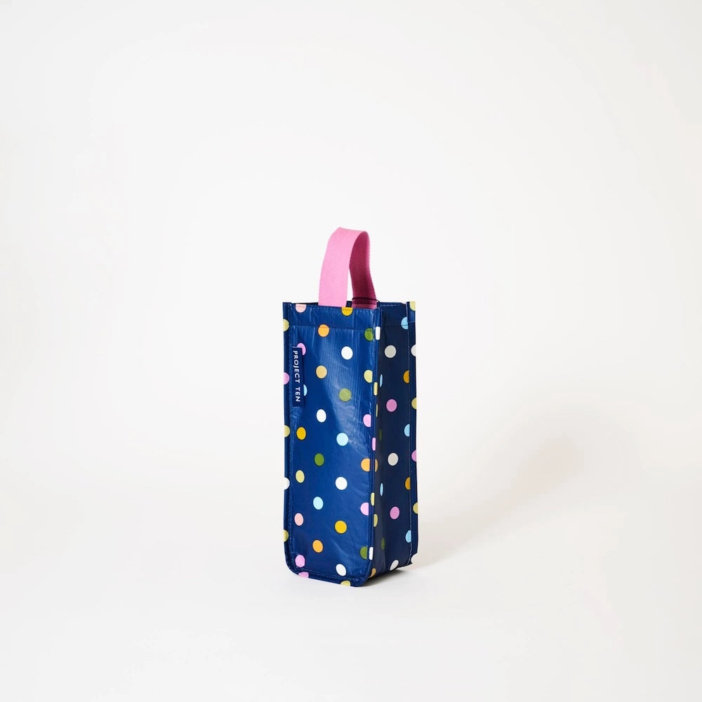 Blue polka dot wine bottle holder with a pink handle on a white background