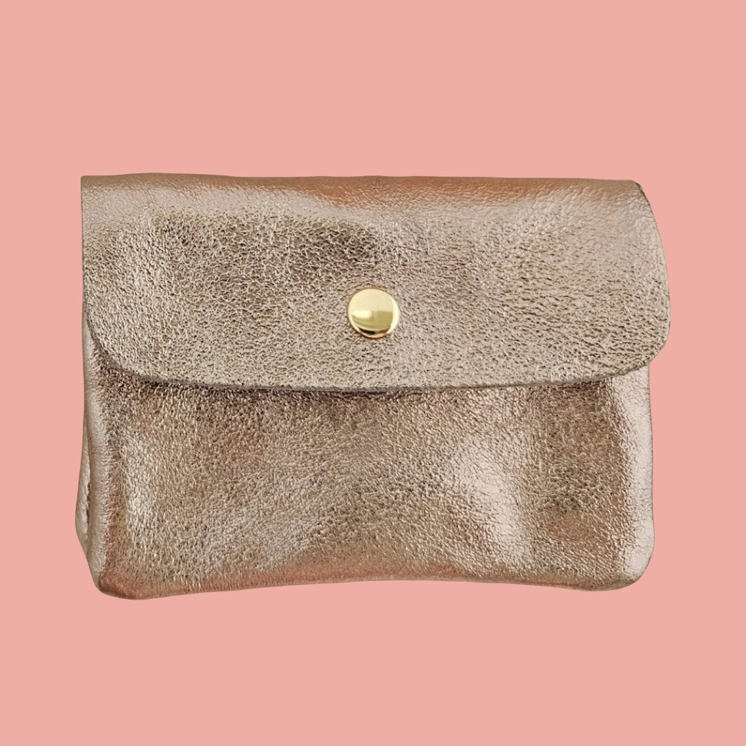 A metallic rose gold leather pouch with a flap closure and a gold snap button, shown against a solid pink background.