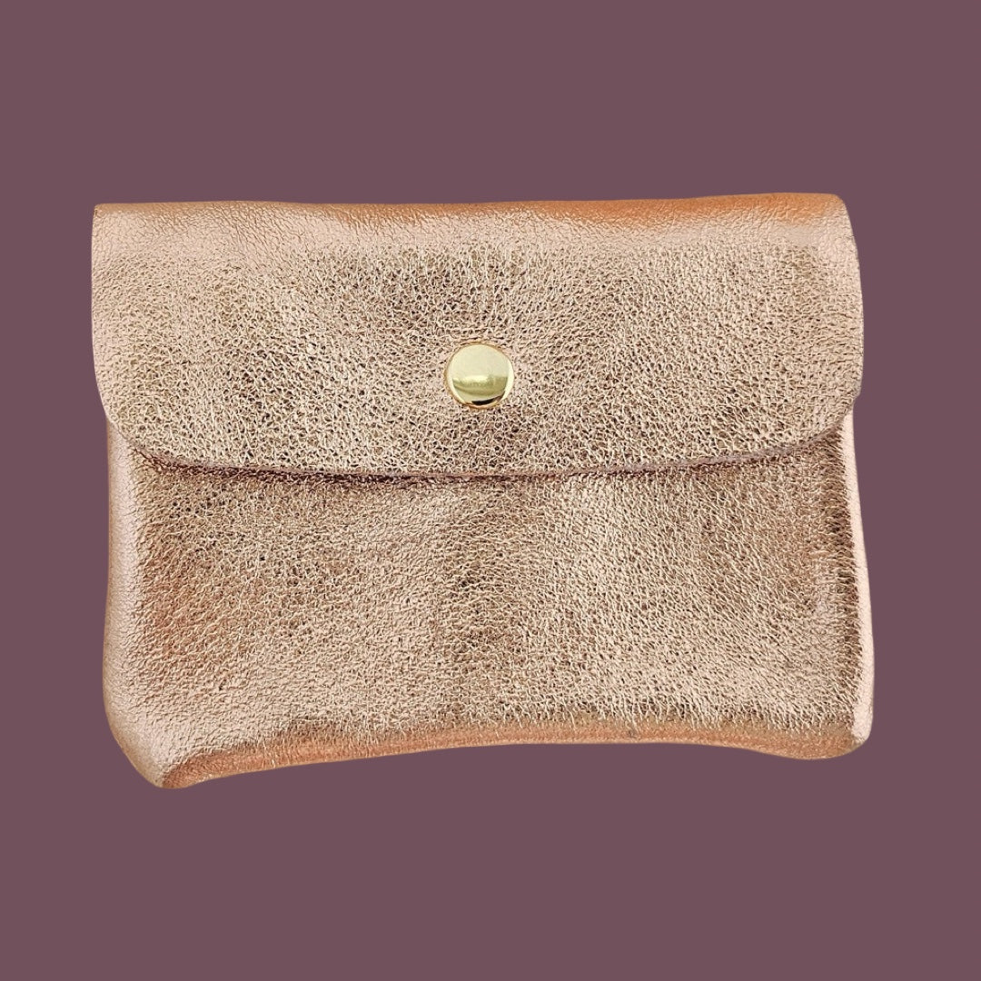 Metallic rose textured clutch bag with a gold button on a dark purple background