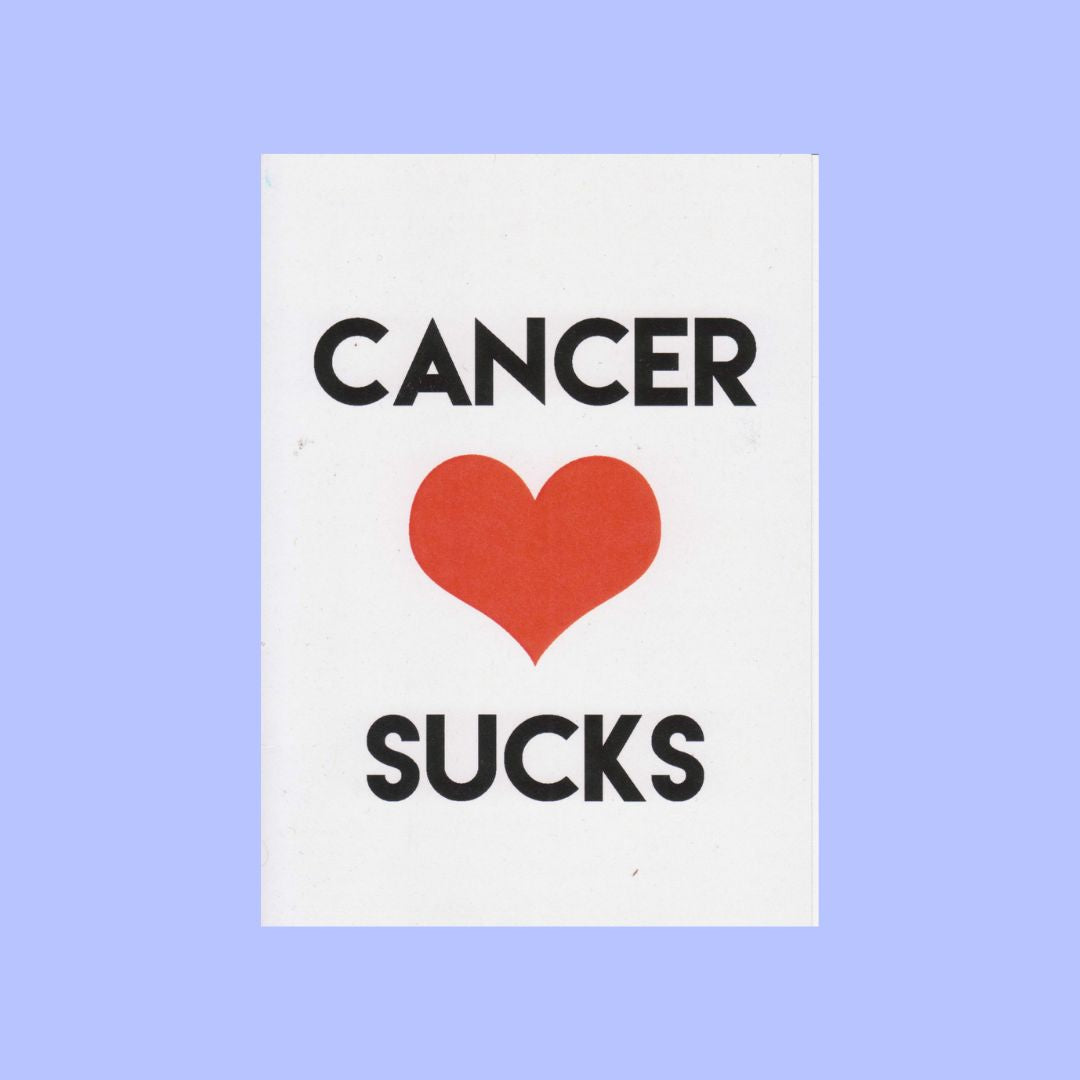 A white rectangular card with the text 'CANCER' above a red heart and 'SUCKS' below, centered on a light periwinkle background.