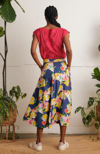 Back view of model wearing Emily & Fin Sandra Picnic Party Skirt paired with a coral coloured top and white sneakers.