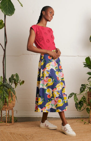Side view of model wearing Emily & Fin Sandra Picnic Party Skirt paired with a coral coloured top and white sneakers
