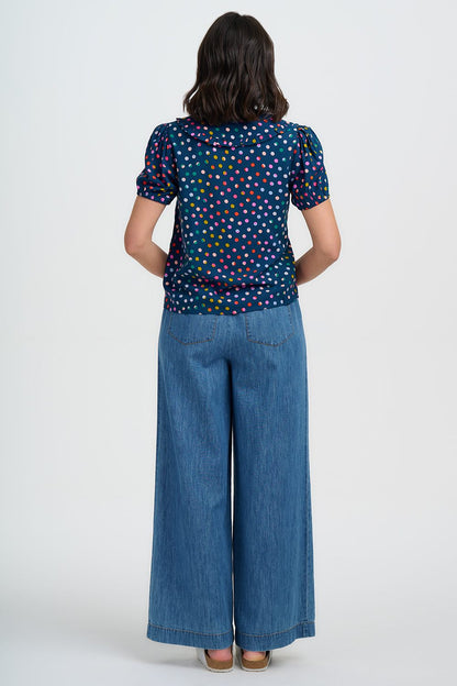 Back view of Person wearing a colorful polka dot shirt and blue jeans on a white background