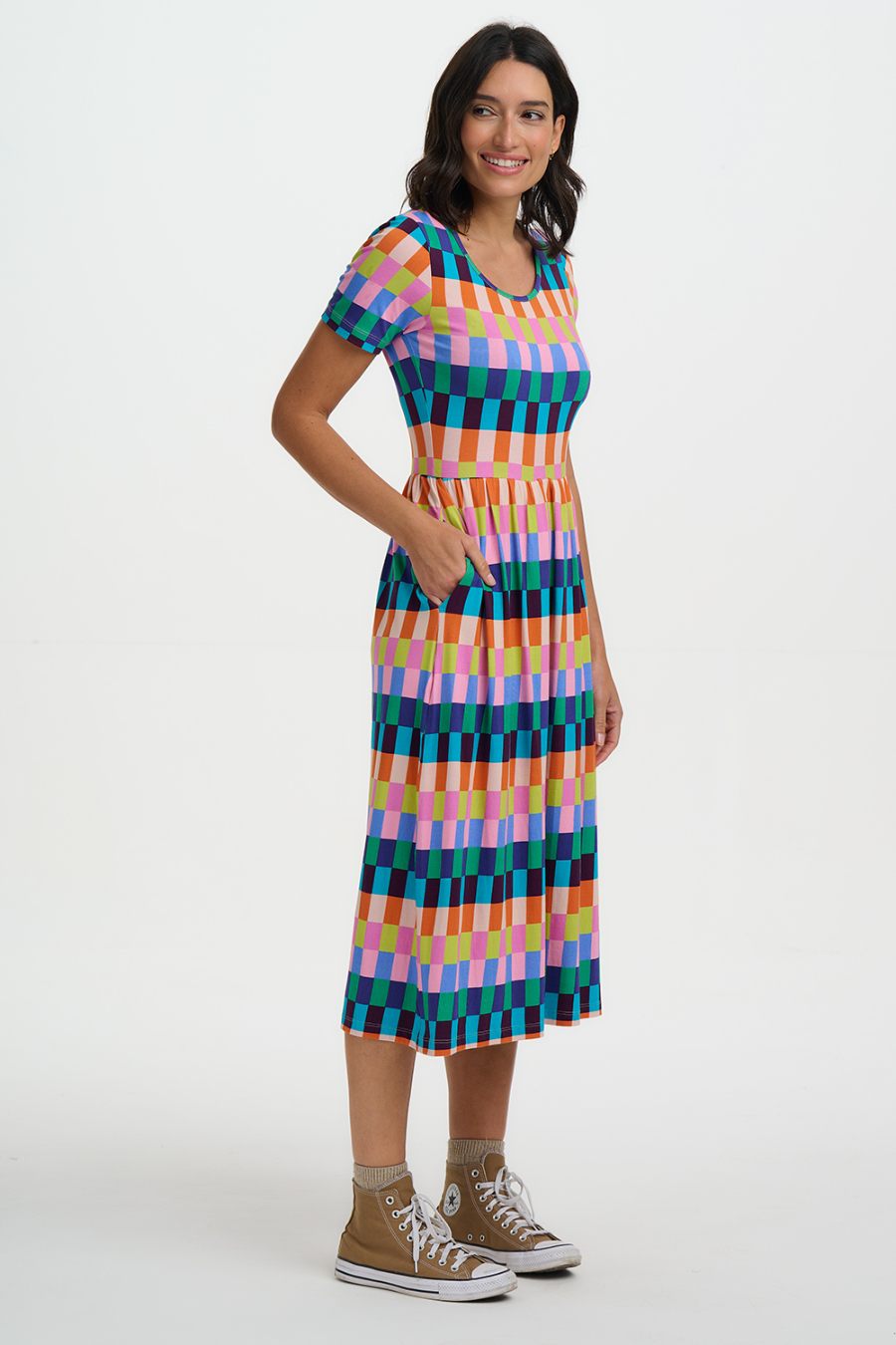 Side view of Woman wearing a colorful checkered dress on a white background