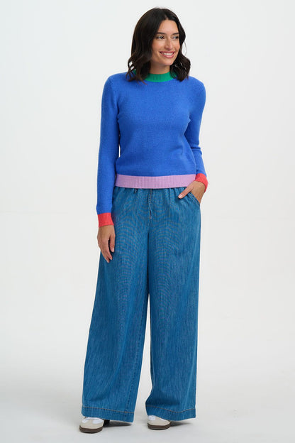 Woman wearing a blue sweater and wide-leg jeans on a white background