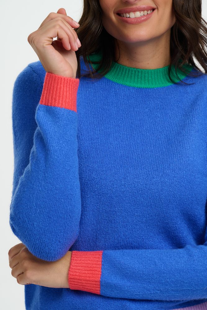Person wearing a blue sweater with colorful cuffs on a white background