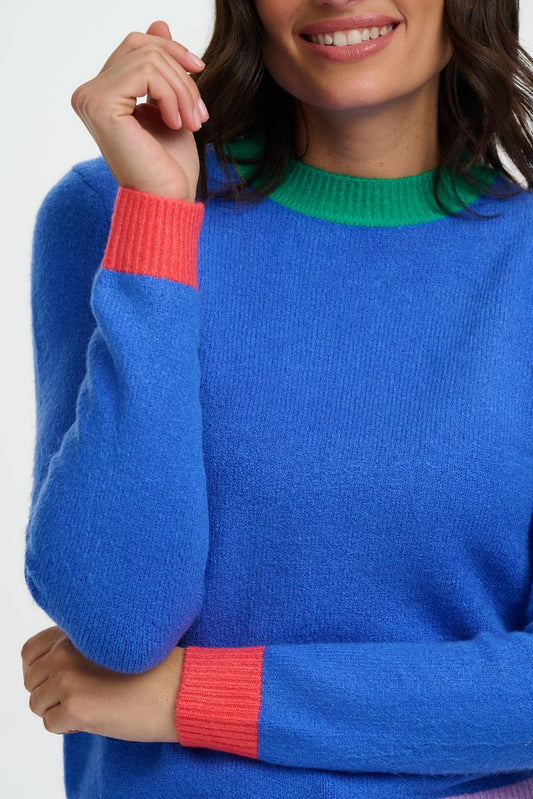 Person wearing a blue sweater with colorful cuffs on a white background