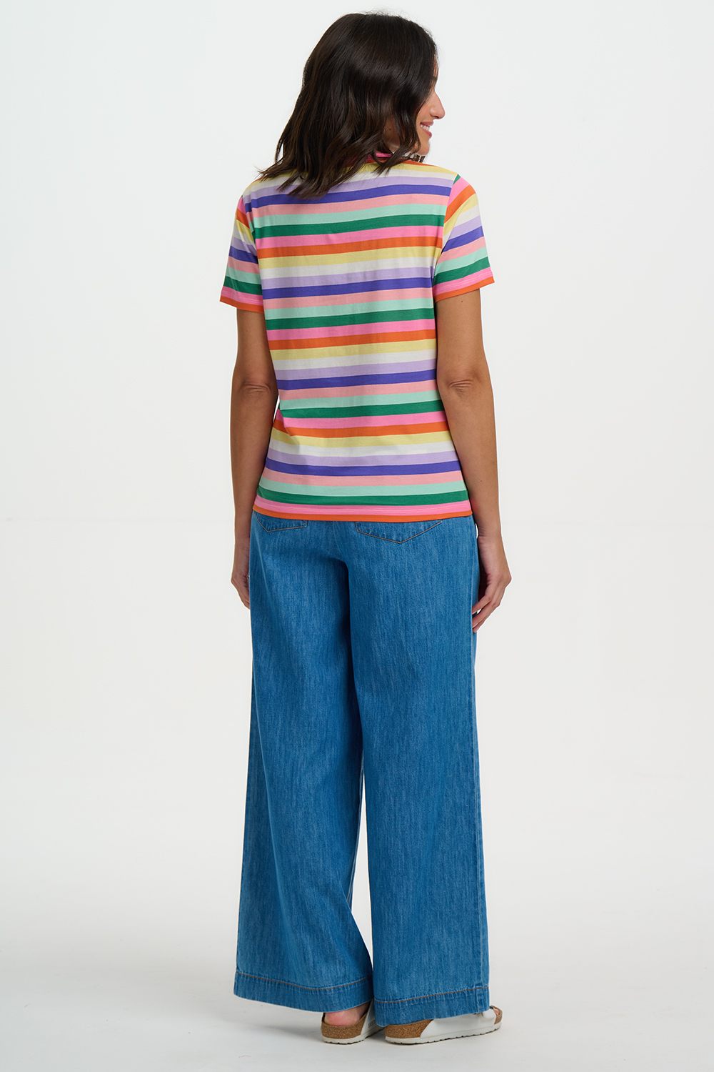Person wearing a colorful striped shirt and blue jeans on a white background