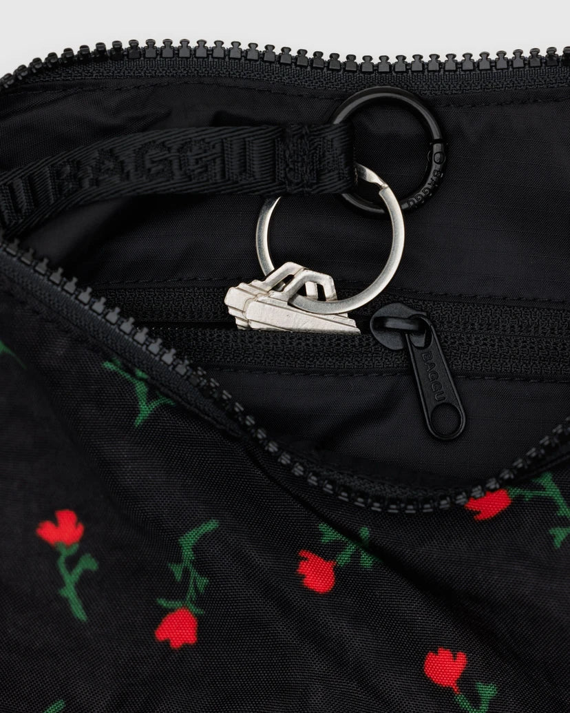 Close up of the inside of the Painted Wildflower bag featuring the red floral patterns of the outside fabric, and black lining with a zipper and a keychain.