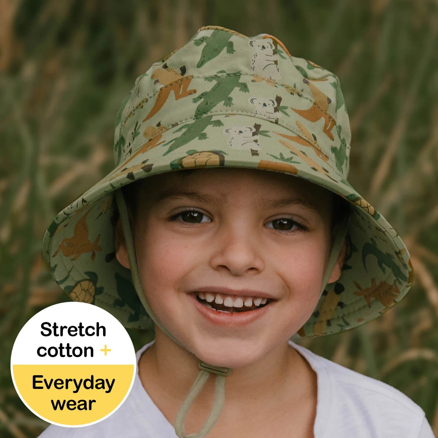 Child wearing a green hat with Australian animal patterns on a blurred natural background