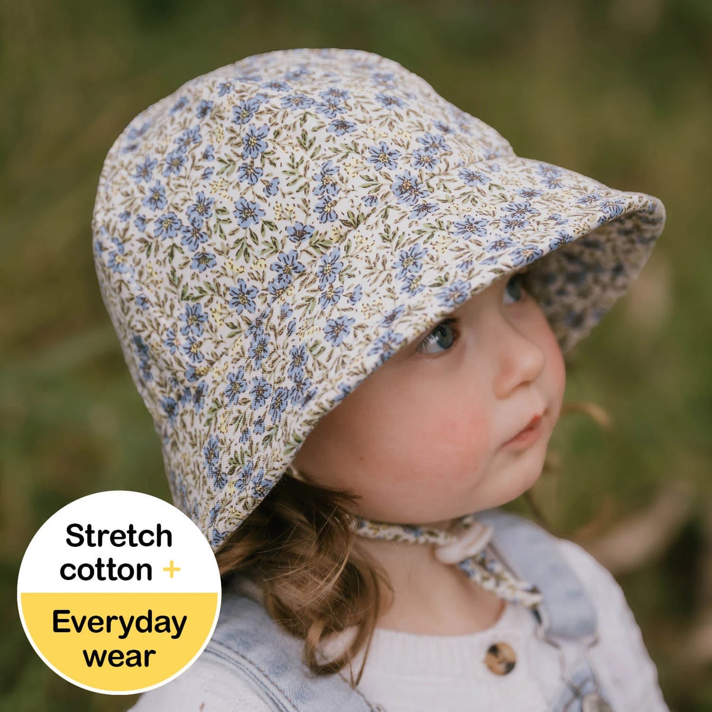 Toddler wearing a floral sun hat with a natural background