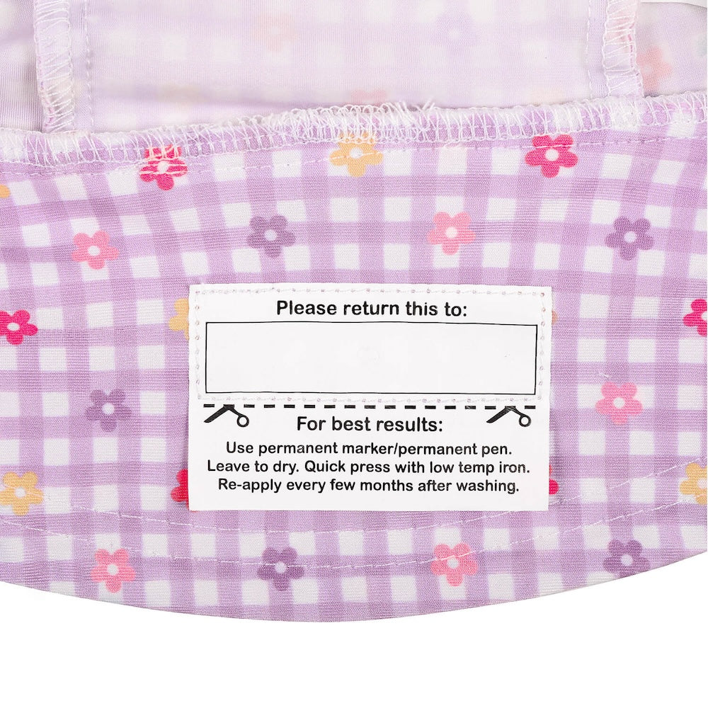 Close-up of the name label inside the brim of a lavender and white gingham swim hat with small pink, purple and yellow floral print.