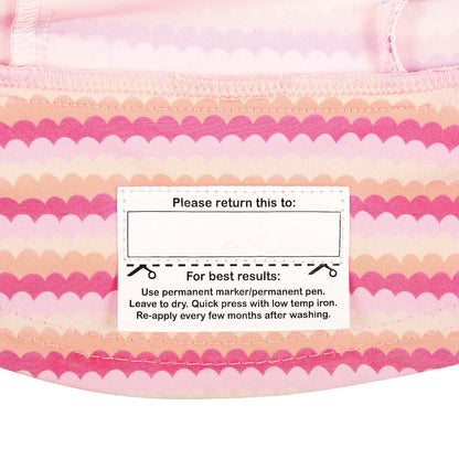 Close-up of the name label on the inside brim of a swim bucket hat with a pink and peach scalloped stripe pattern.