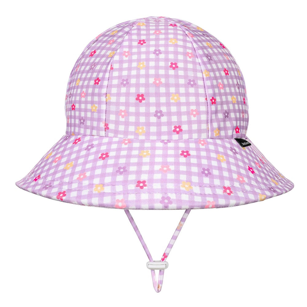 A light purple and white gingham swim bucket hat with a small multicolour floral print, featuring a chin strap and a small black Bedhead tag on the side.