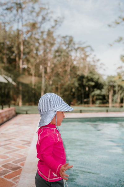 Side view of Bedhead Stevie Stripe Swim Legionnaire Hat worn by a young model on the side of a swimming pool