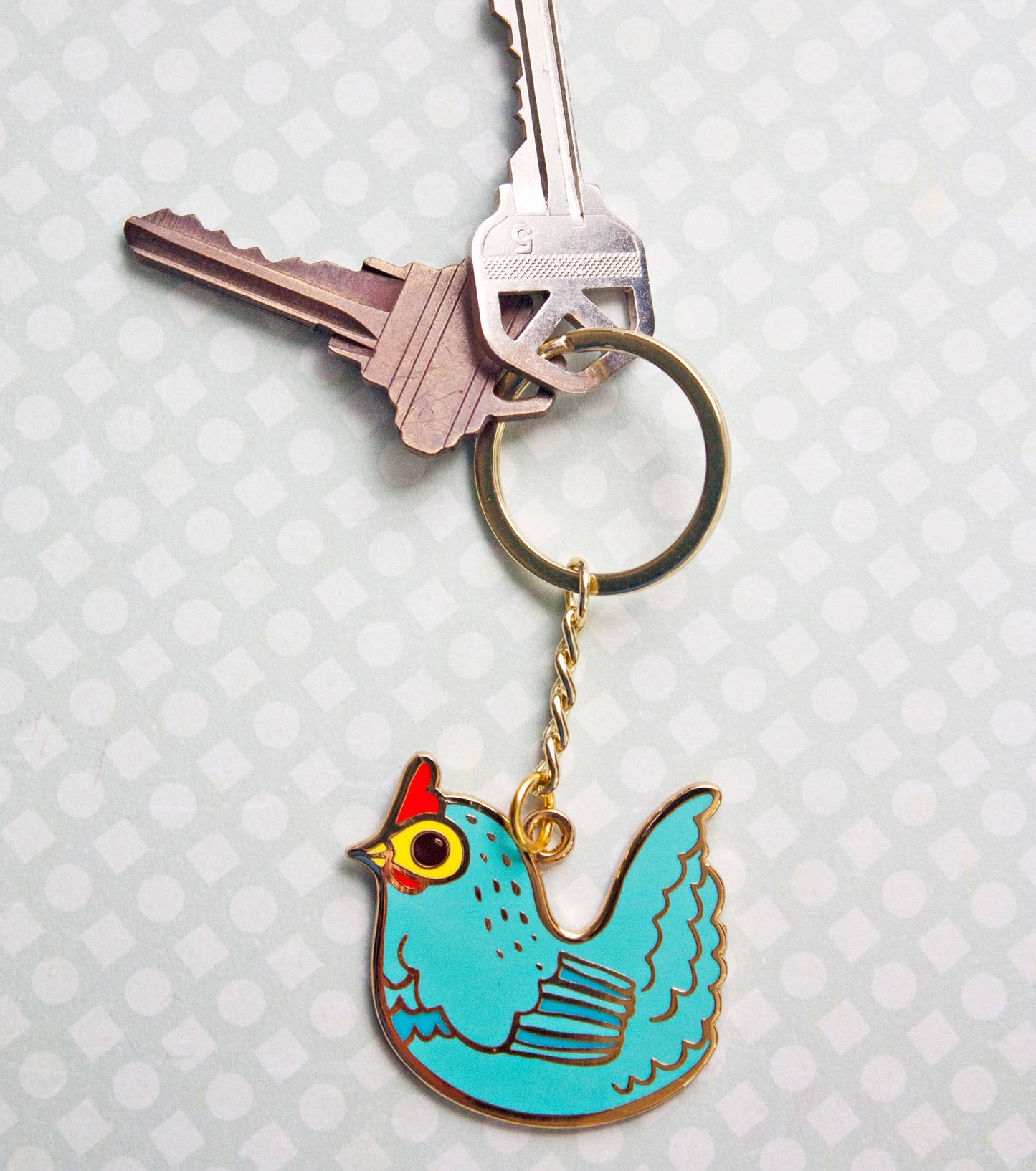Chicken keychain attached to keys on a light gray background.