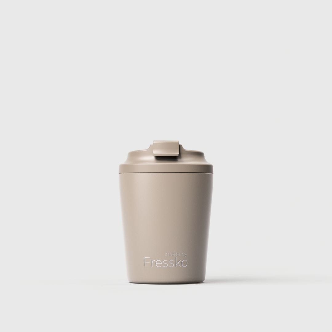 A matte beige-taupe reusable travel tumbler with a matching flip-top lid, featuring the Fressko brand name printed in white near the bottom, set against a clean light gray background.