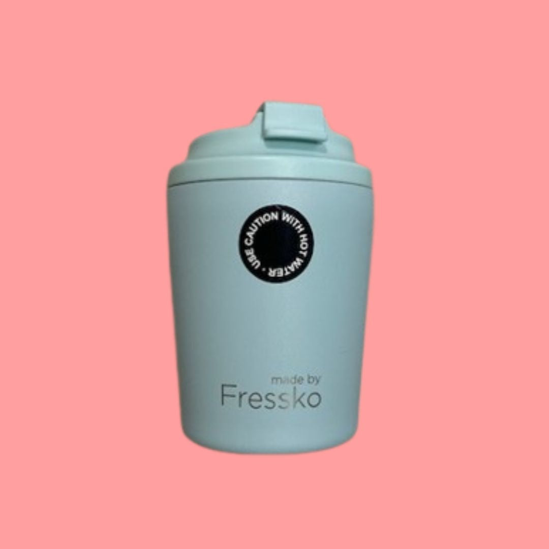 Light blue reusable cup with a black label on a pink background