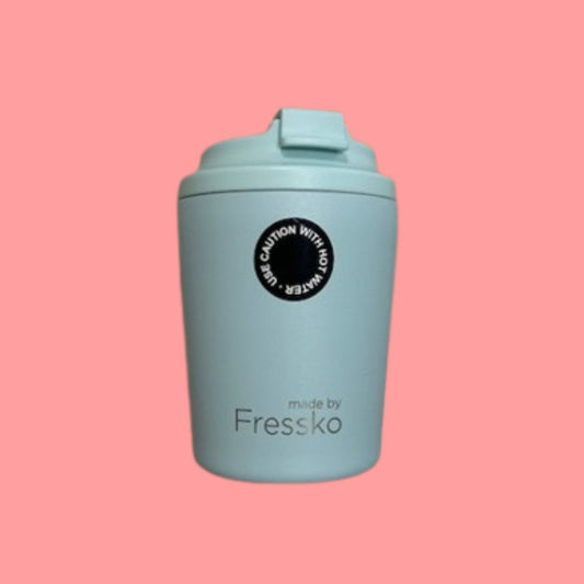 Light blue reusable cup with a black label on a pink background