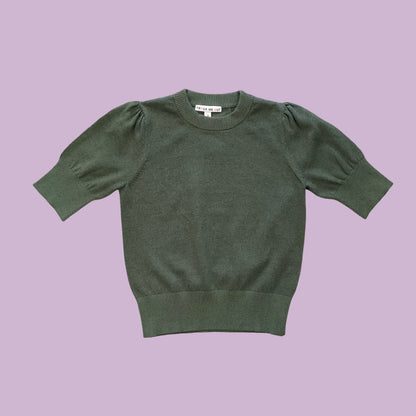 Frock Me Out Lurex Knit, a short-sleeved knit with puff sleeves in Olive, on a pale lilac background